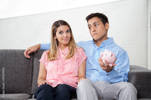 Man Holding Piggybank While Sitting With Woman