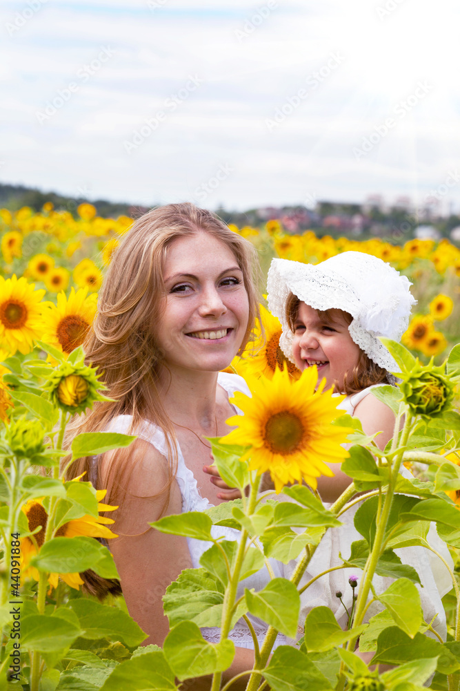 Happy mother with the daughter in the field with sunflowers Happy mother with the daughter in the field with sunflowers