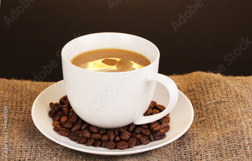 Cup of coffee on sacking on brown background