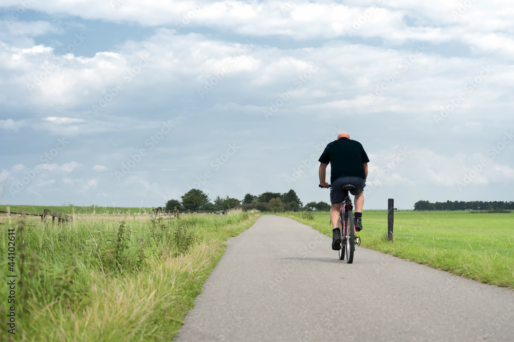 Man riding a bike through the fields
