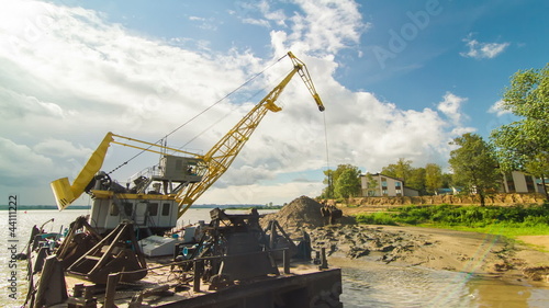Floating crane digging sand on river side