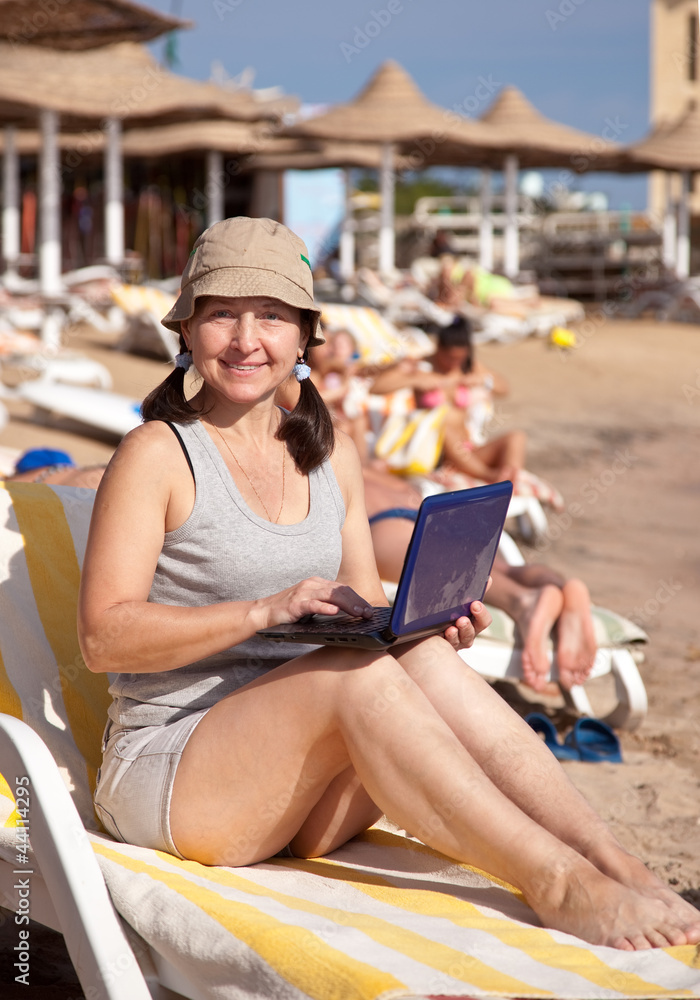 mature woman  with laptop at resort beach