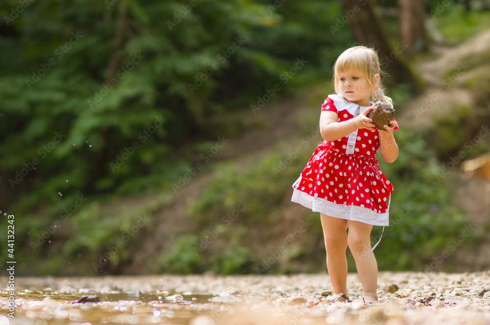 Naklejka premium Adorable girl throw stone to river stream in park