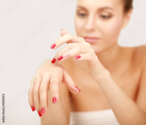 A beautiful woman is applying cream on her hand