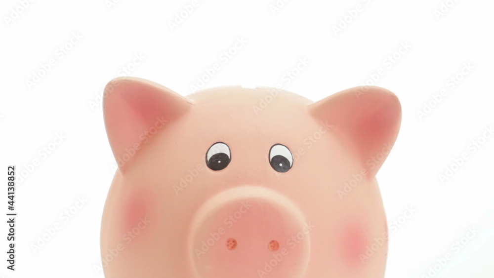 Saving money: hand putting coins in a piggy bank. Isolated Saving money: hand putting coins in a piggy bank. Isolated