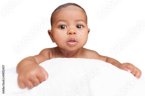 Baby peeping over the pillow in a white background