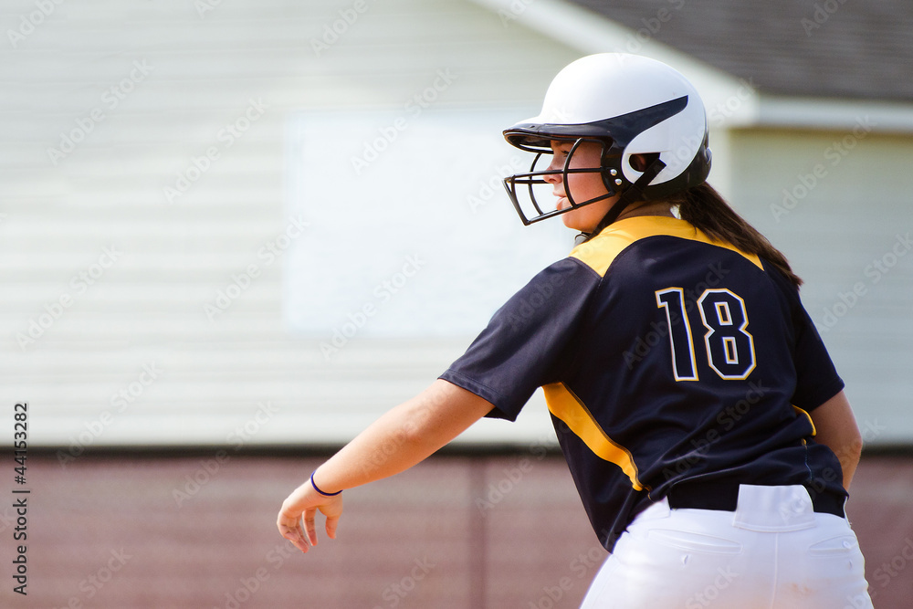 Fototapeta premium Young teen girl playing softball in organized game