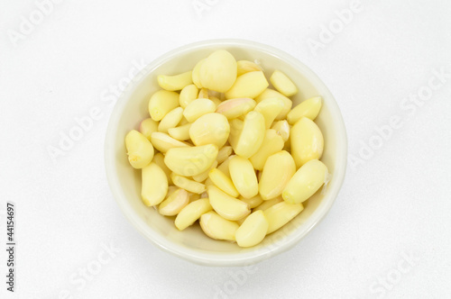 Fresh peeled garlic in a bowl, isolated on white background.