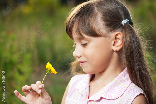 Cute little girl playing with a flower