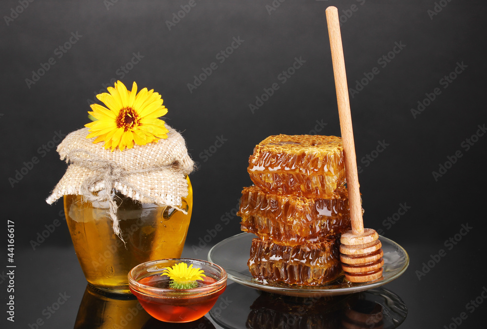 Jar of honey and honeycomb on black background Jar of honey and honeycomb on black background