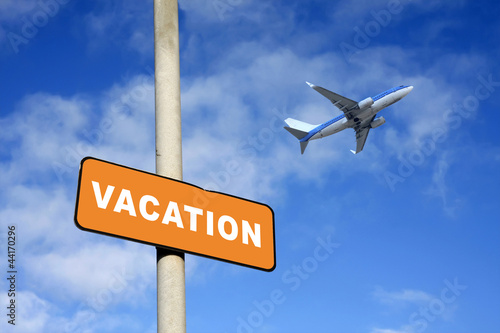 Vacation sign and plane against a blue sky