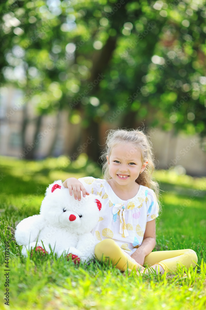 Cute little girl smiling in a park hugging a toy bear Cute little girl smiling in a park hugging a toy bear