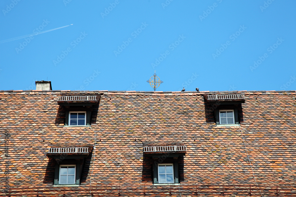 Naklejka premium Roof with shuttered windows on blue sky background
