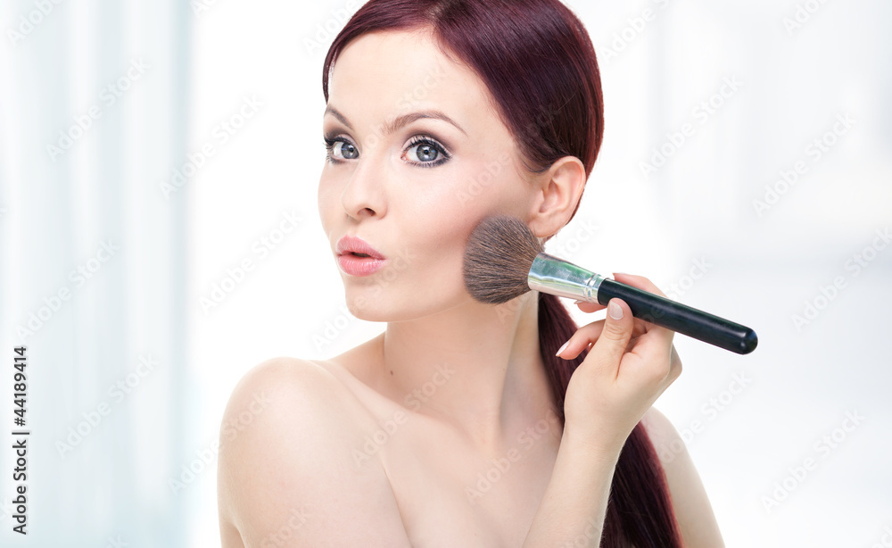 Portrait of attractive young woman applying blusher Portrait of attractive young woman applying blusher