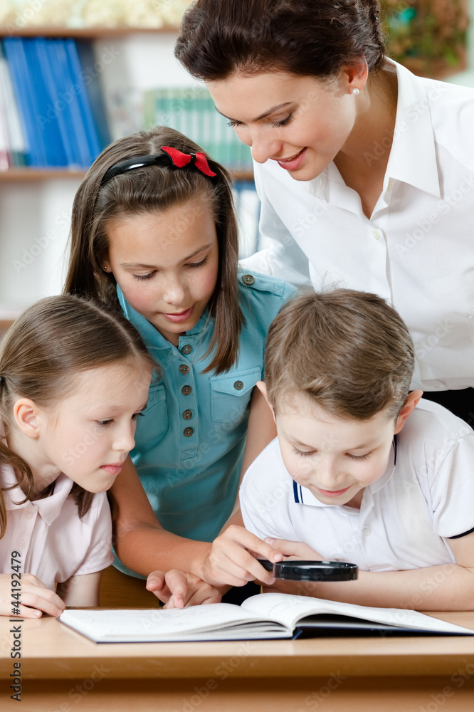 Young teacher with her pupils examine something Young teacher with her pupils examine something
