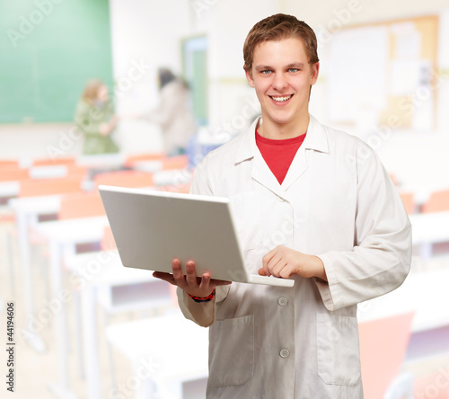 portrait of young student holding laptop at classroom