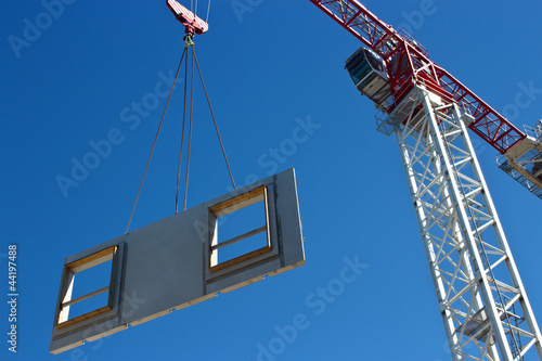 Obraz na płótnie Tower crane is lifting preacast concrete panel w salonie