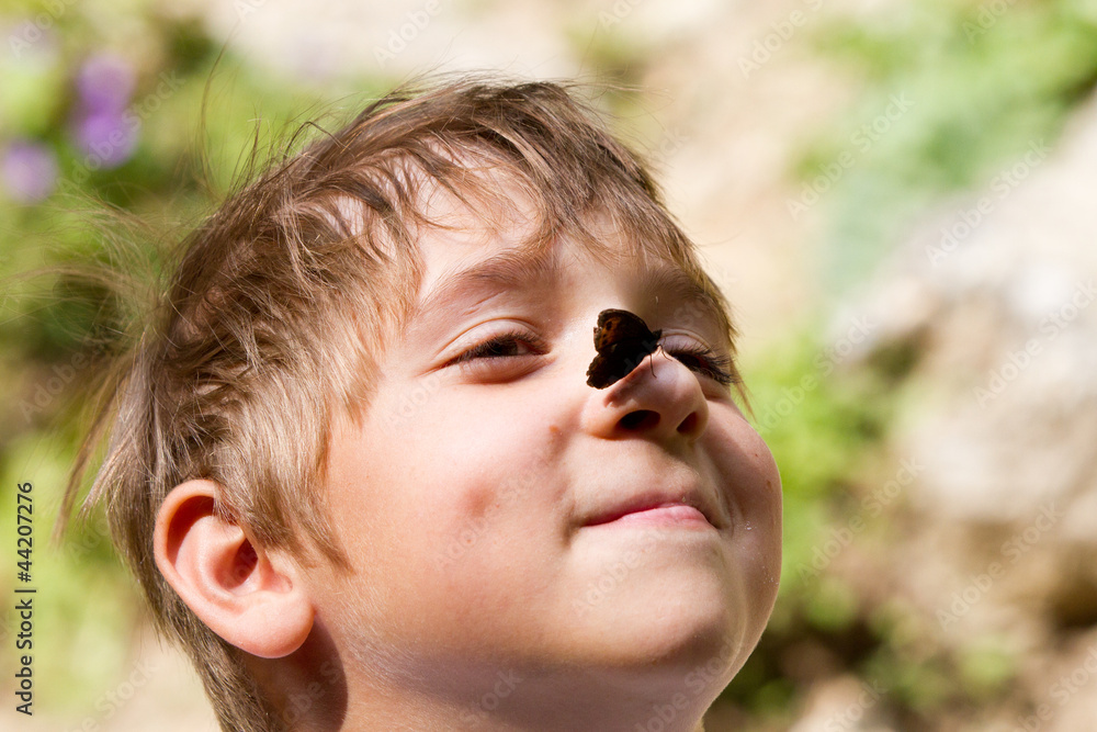 Young boy smiling with butterfly on his nose in summer Young boy smiling with butterfly on his nose in summer