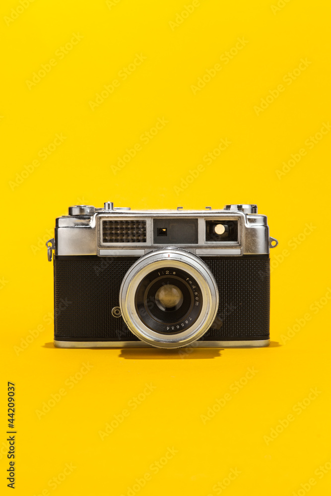 Retro analog film camera on yellow background