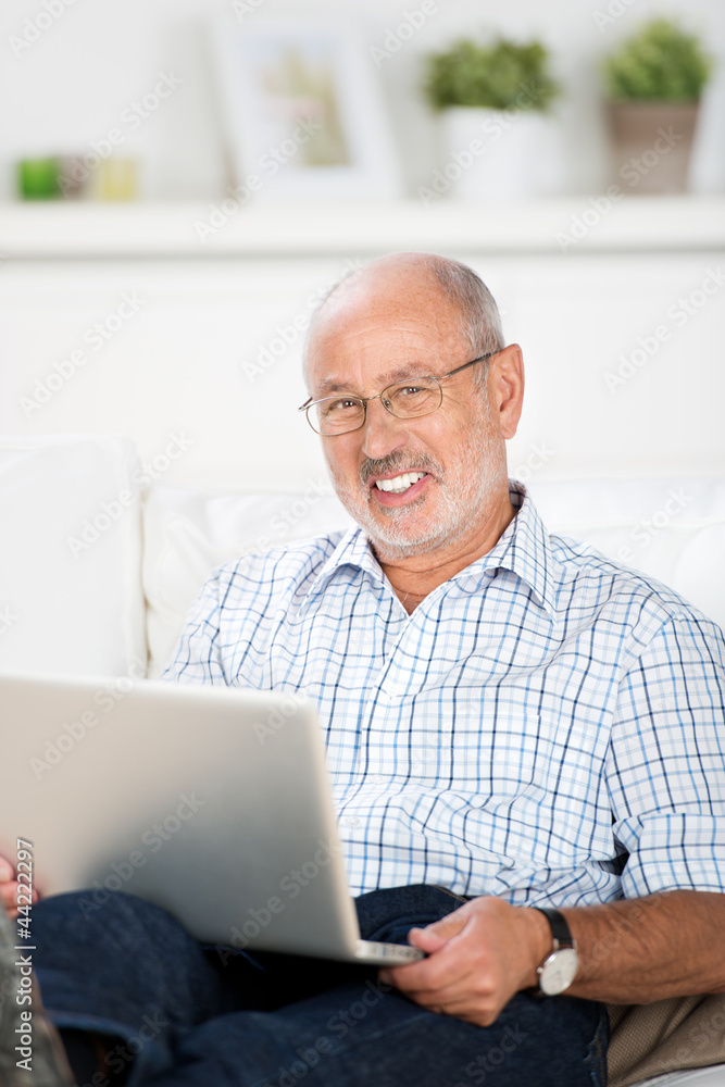 senior sitzt entspannt mit laptop auf dem sofa senior sitzt entspannt mit laptop auf dem sofa