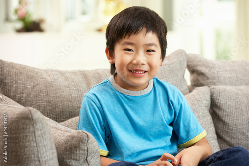Young Chinese Boy Sitting On Sofa At Home