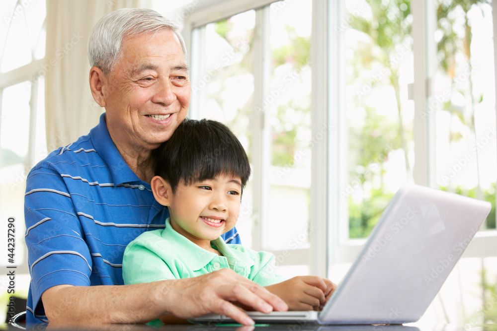 Chinese Grandfather And Grandson Sitting At Desk Using Laptop Chinese Grandfather And Grandson Sitting At Desk Using Laptop