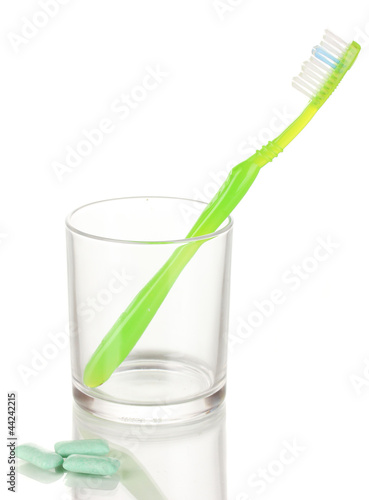 Toothbrush in glass and chewing gum isolated on white