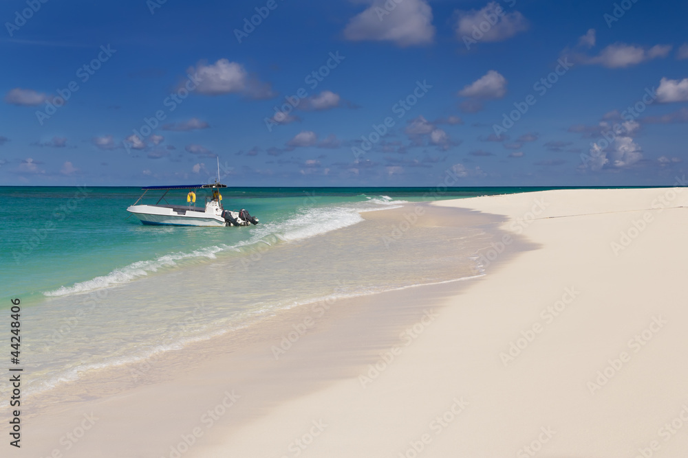 Tropical sandy beach at summer sunny day with boat on background