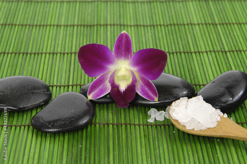orchid with zen stone and sea salt in spoon on mat orchid with zen stone and sea salt in spoon on mat