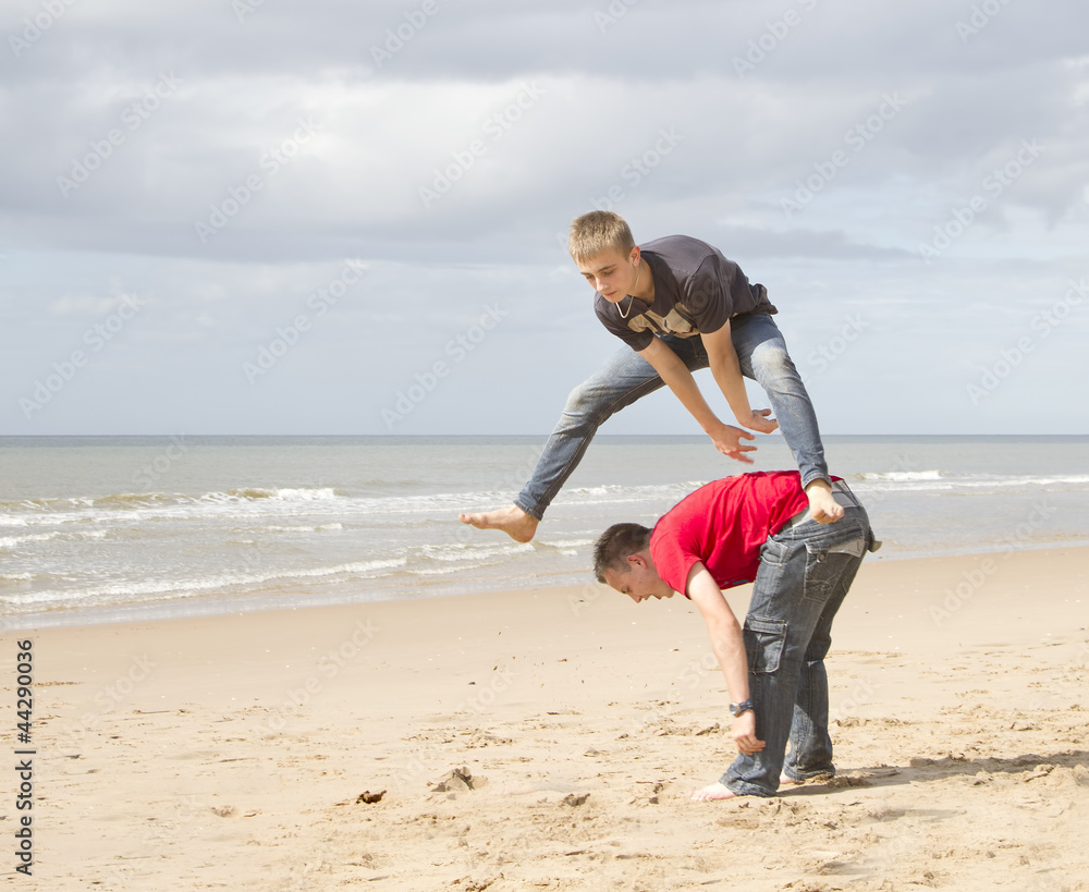 Αυτοκόλλητο Two teenage lads playing leapfrog on the beach