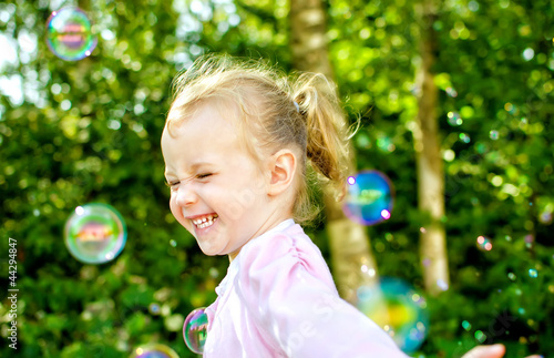 Little girl having fun with soap bubbles in the park