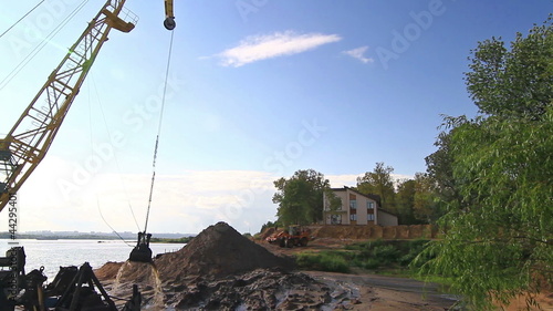 Floating crane digging sand on river side