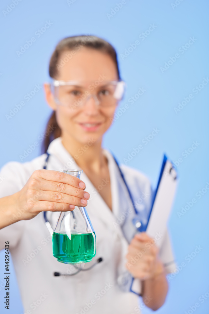 Young woman therapeutic doctor showing medical retort with green Young woman therapeutic doctor showing medical retort with green