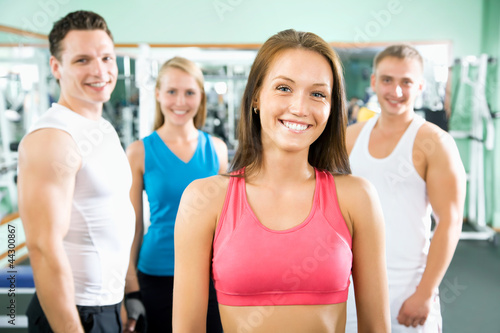 Woman smiling in front of a group of gym people