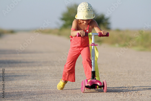 young happy girl traveling on scooter by road photo