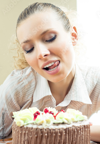 Cheerful blond young woman eating torte