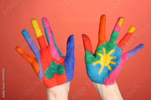 Brightly colored hands on red background close-up