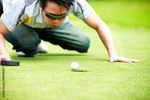 Golf player cheating blowing to get the ball into the hole