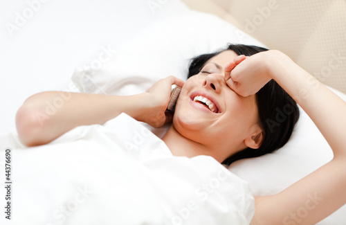 Woman in underwear speaks on cellular while lying in the bed