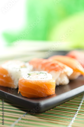 Black rectangle plate with sushi rolls, isolated on white