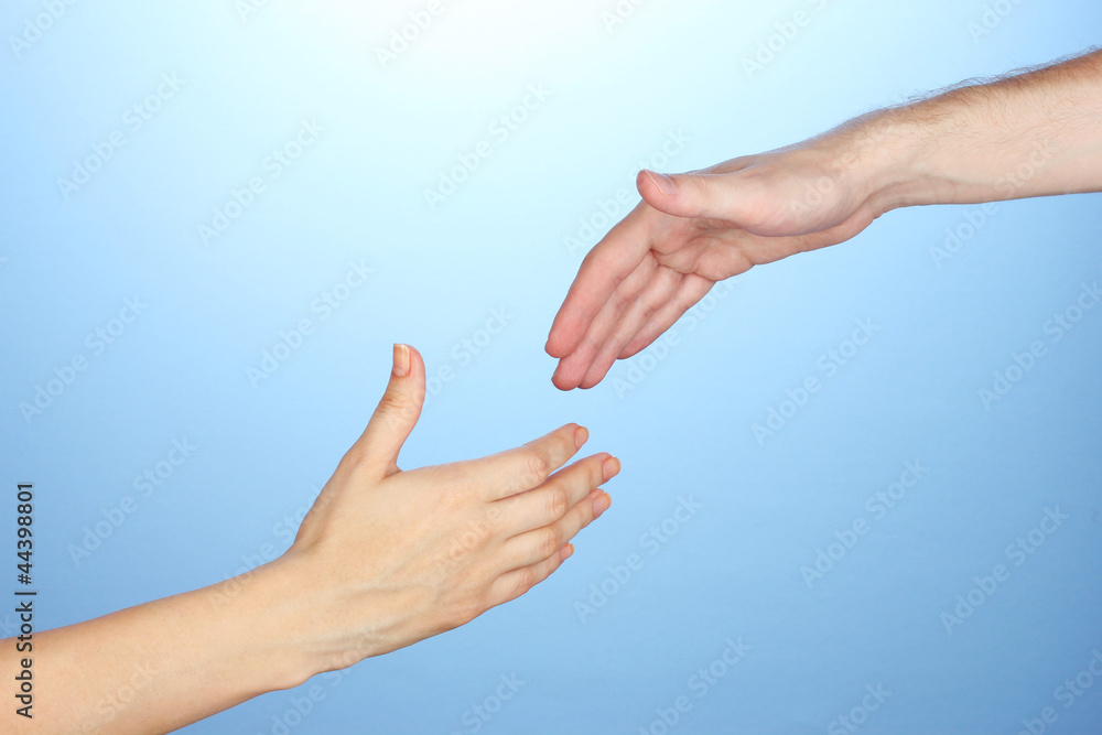 Women's hand goes to the man's hand on blue background