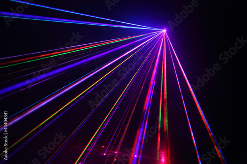 Lot of beautiful multi-colored laser beams in dark at disco. photo