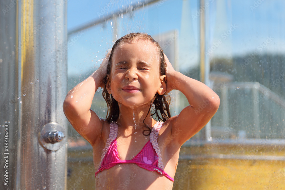Little girl dressed in swimsuit takes shower after swimming Stock Photo
