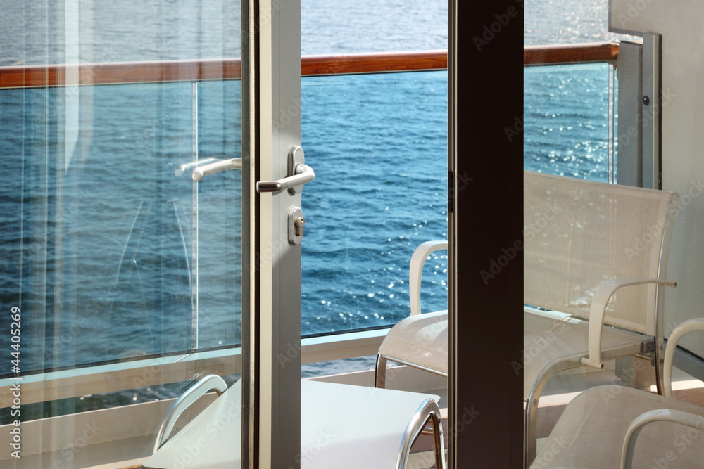 open door; glassy balcony with white chairs and table on liner