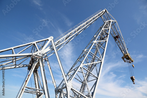 big white hoisting crane with hook at background of blue sky photo