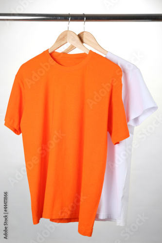 Orange and white t-shirts on hanger on white background