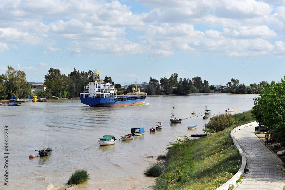 Naklejka premium Barco mercante navegando por el río Guadalquivir desde el puerto de Sevilla hacia el Oceano Atlántico