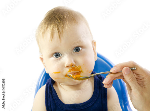 A young gray-eyed child feeding pumpkin puree