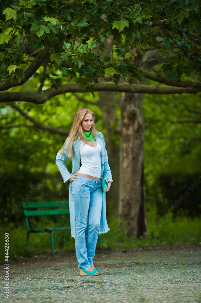 attractive young woman in jeans walking in the park