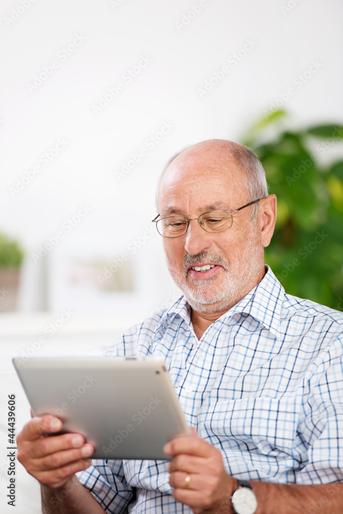 lächelner älterer mann schaut auf sein tablet lächelner älterer mann schaut auf sein tablet